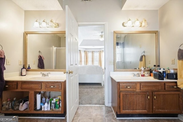 full bath featuring two vanities, connected bathroom, ceiling fan, and a sink