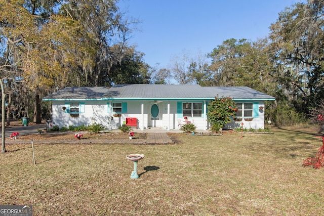 ranch-style home featuring metal roof and a front lawn