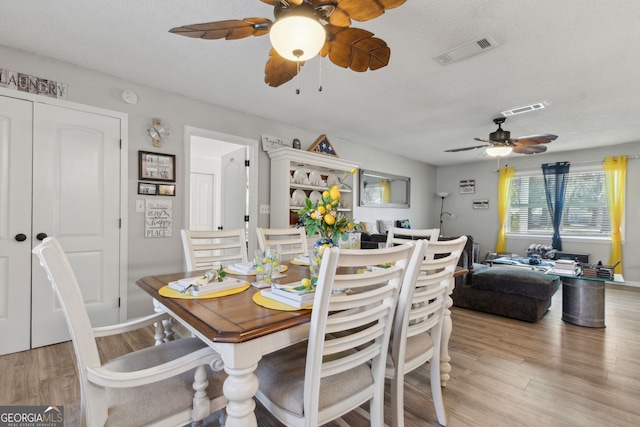 dining space with a ceiling fan, visible vents, and light wood-type flooring