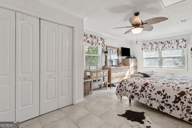 bedroom featuring visible vents, crown molding, light tile patterned flooring, a closet, and a textured ceiling