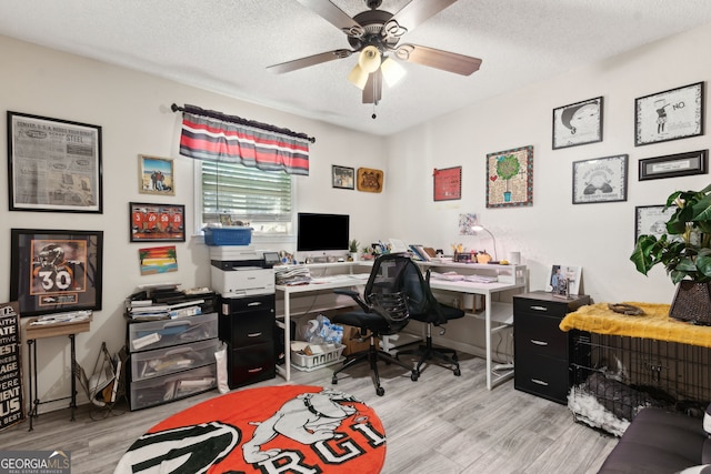 office area with baseboards, light wood-style flooring, a textured ceiling, and ceiling fan