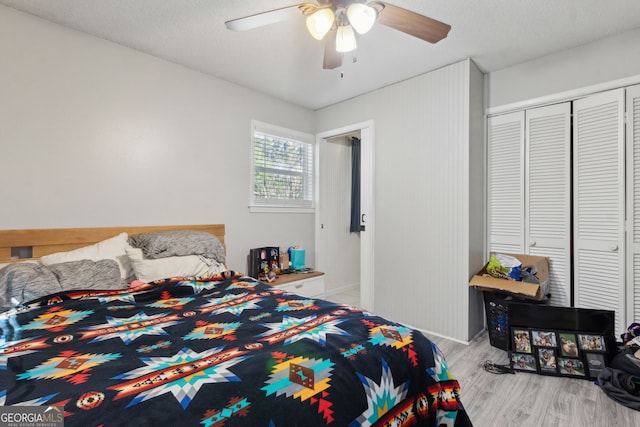 bedroom with a textured ceiling, a closet, light wood finished floors, and ceiling fan