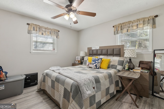 bedroom with multiple windows, a ceiling fan, and wood finished floors