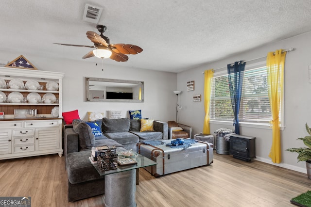 living room with visible vents, a textured ceiling, wood finished floors, and a ceiling fan