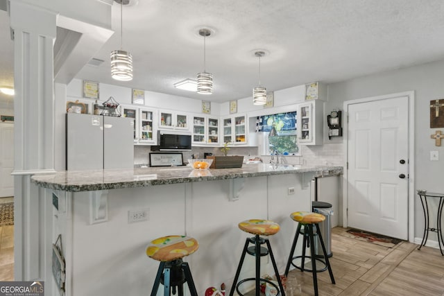 kitchen with glass insert cabinets, light wood finished floors, a breakfast bar, and white cabinetry