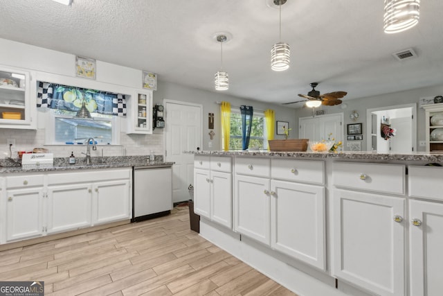 kitchen featuring decorative backsplash, light wood-style floors, white cabinets, a ceiling fan, and a sink