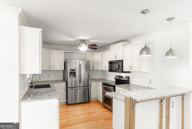 kitchen featuring light wood finished floors, a peninsula, a sink, ceiling fan, and appliances with stainless steel finishes