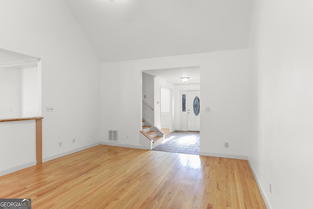 unfurnished room featuring visible vents, baseboards, stairs, vaulted ceiling, and wood finished floors