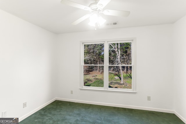 unfurnished room with a wealth of natural light, visible vents, a ceiling fan, and dark colored carpet