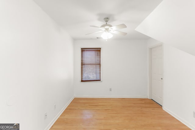 spare room featuring light wood-style flooring, a ceiling fan, and baseboards