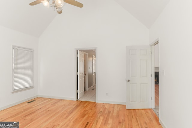 unfurnished bedroom with visible vents, high vaulted ceiling, baseboards, and wood finished floors