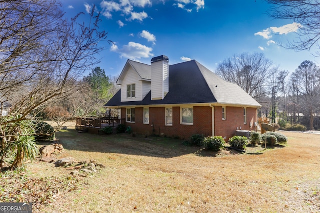 view of side of home featuring a lawn, a wooden deck, brick siding, central AC unit, and a chimney