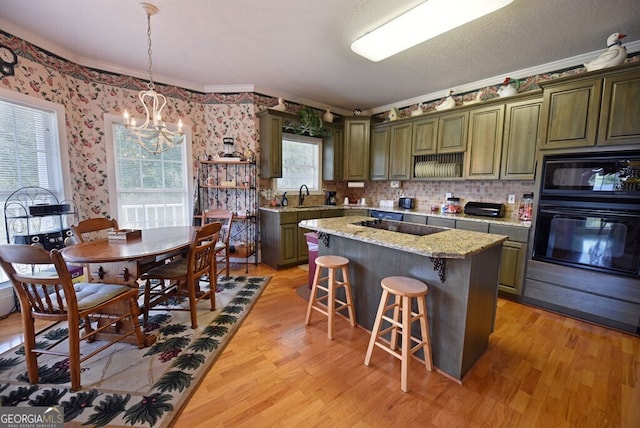 kitchen featuring a sink, a notable chandelier, black appliances, and light wood finished floors