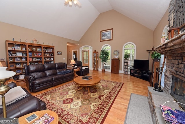 living room with ceiling fan, high vaulted ceiling, wood finished floors, and a fireplace