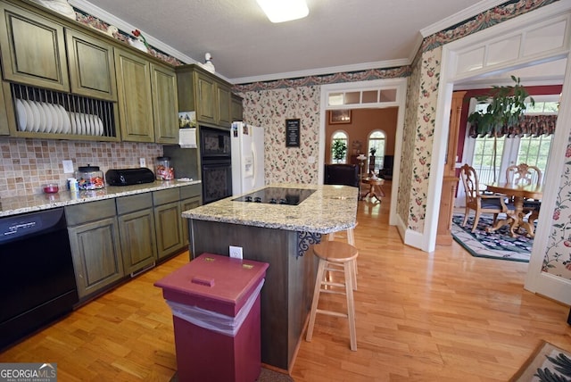 kitchen with black appliances, a breakfast bar, plenty of natural light, crown molding, and wallpapered walls