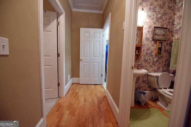 hallway with baseboards, light wood-style floors, ornamental molding, and wallpapered walls