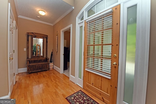 foyer entrance with light wood-type flooring, baseboards, a textured ceiling, and crown molding