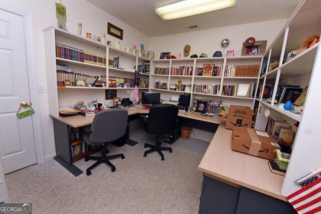 carpeted home office with visible vents and built in desk