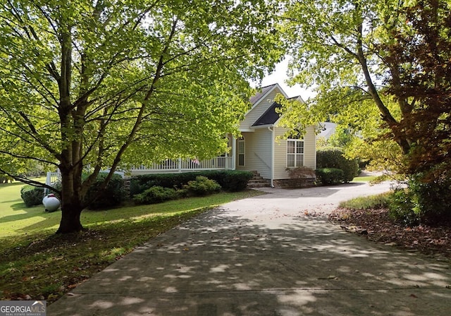 view of front of property with concrete driveway, covered porch, and a front yard