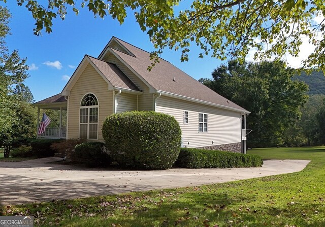 view of home's exterior with a yard and a shingled roof