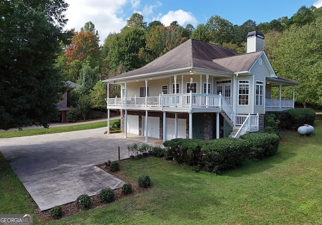 back of house with a yard, a garage, a porch, and a chimney