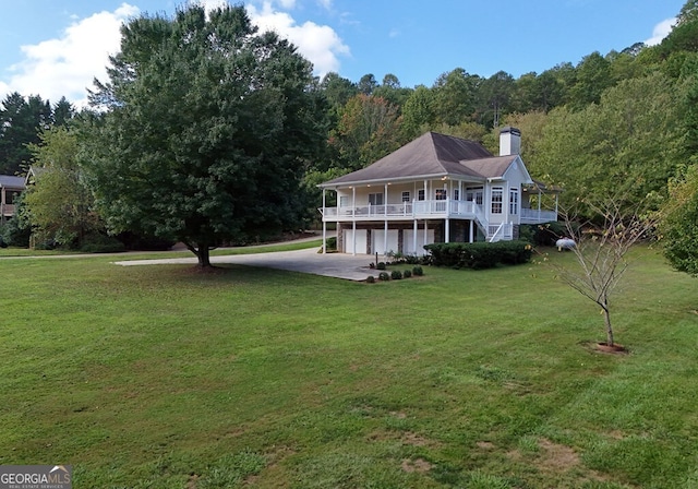 rear view of property with a lawn, a view of trees, stairway, a garage, and a chimney