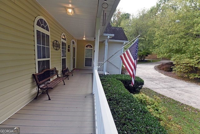 wooden terrace featuring a porch and concrete driveway