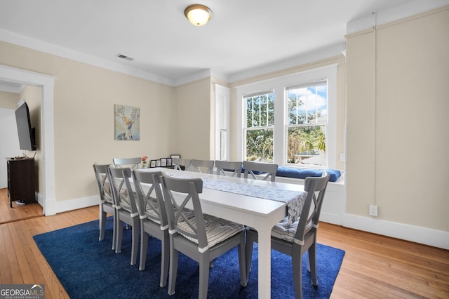 dining area featuring visible vents, baseboards, light wood-style floors, and ornamental molding