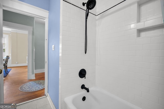 bathroom featuring baseboards, bathing tub / shower combination, and wood finished floors