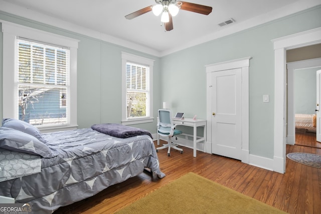 bedroom featuring visible vents, ceiling fan, baseboards, and wood finished floors