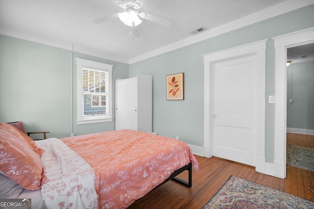 bedroom featuring visible vents, wood-type flooring, baseboards, and crown molding