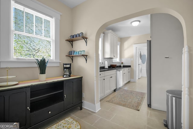 kitchen featuring arched walkways, dishwasher, white cabinetry, and open shelves