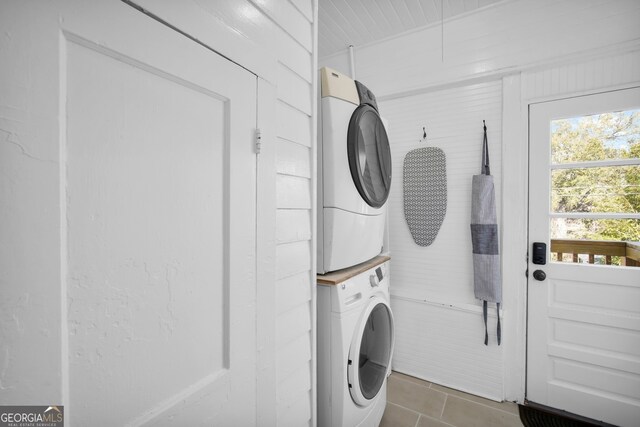 washroom featuring stacked washer and dryer, laundry area, and tile patterned flooring