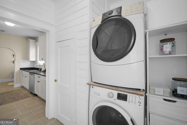 laundry room featuring visible vents, wood tiled floor, laundry area, stacked washer and clothes dryer, and a sink