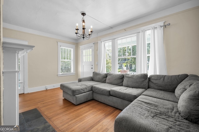 living room featuring a chandelier, baseboards, and wood finished floors