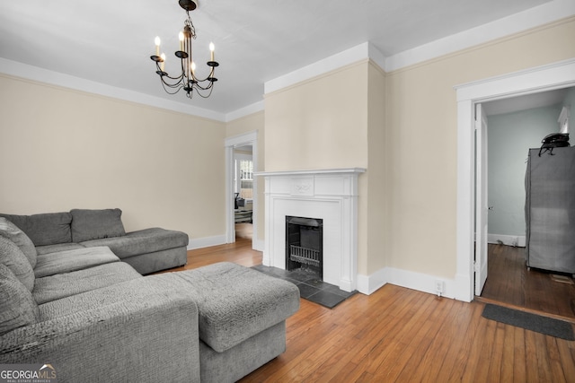 living area with baseboards, wood-type flooring, a chandelier, and a fireplace