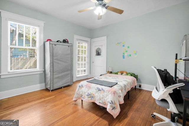 bedroom featuring multiple windows, light wood-style floors, and baseboards