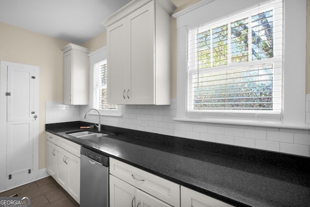 kitchen featuring dark countertops, a sink, backsplash, white cabinetry, and stainless steel dishwasher