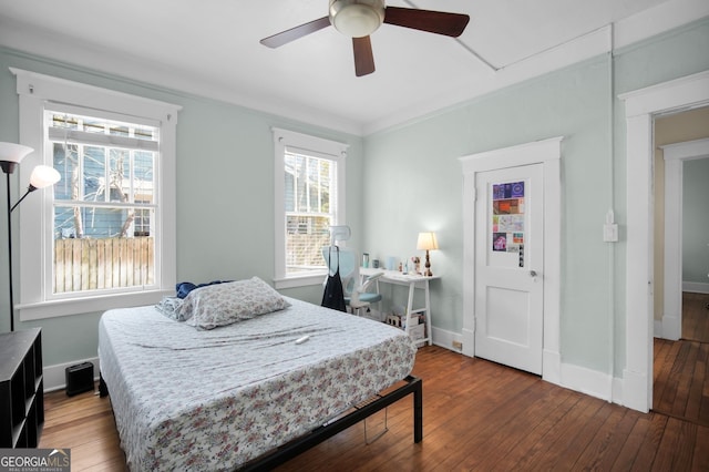 bedroom featuring baseboards, wood-type flooring, ornamental molding, and a ceiling fan