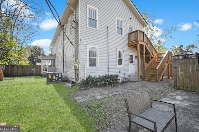 back of property with a fenced backyard, stairway, and a yard