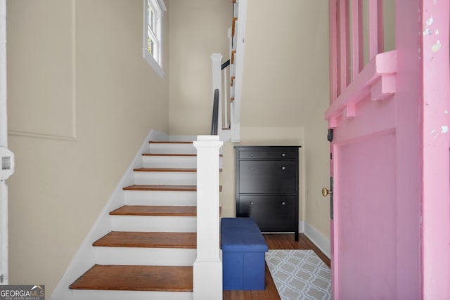 stairway with wood finished floors and baseboards