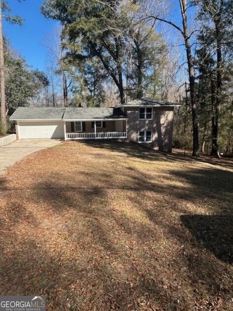 split level home with an attached garage, concrete driveway, and a front yard