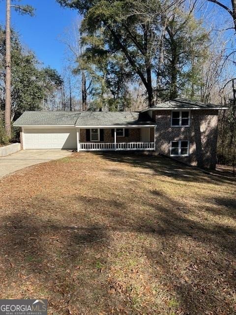 tri-level home with a front lawn, a porch, concrete driveway, and a garage