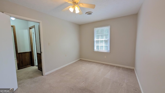 empty room with baseboards, visible vents, ceiling fan, a textured ceiling, and carpet flooring