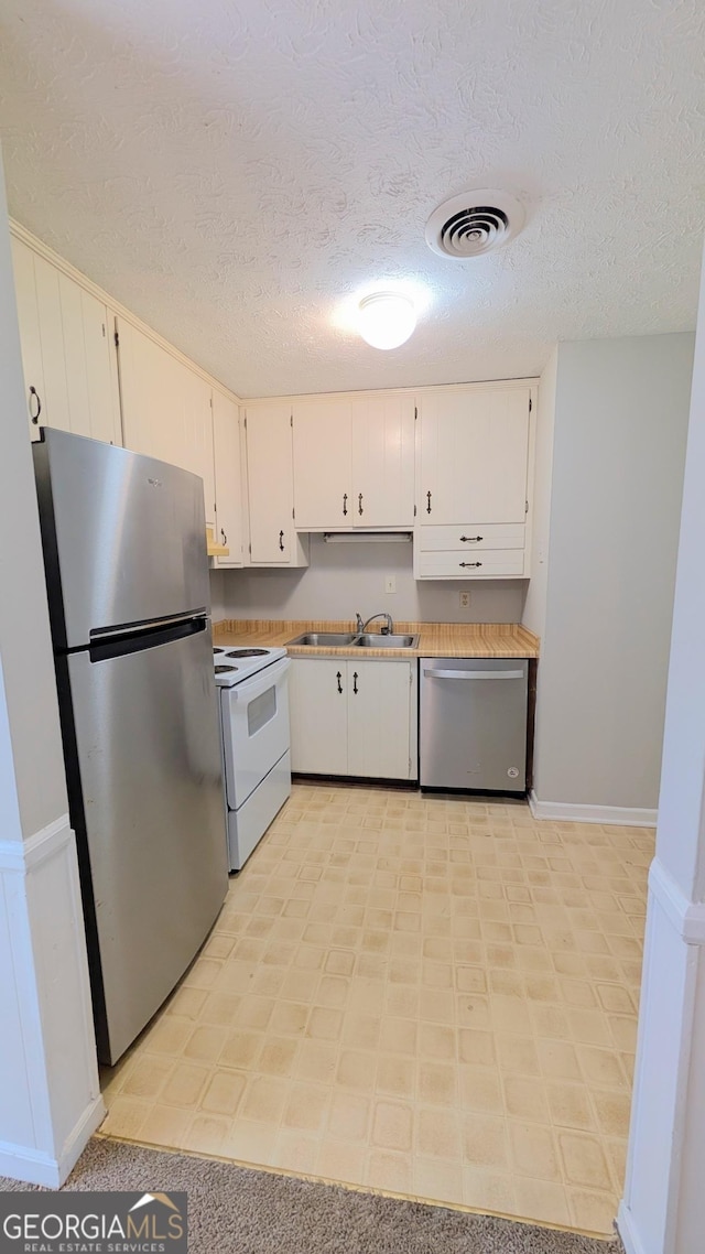 kitchen with visible vents, a sink, white cabinetry, stainless steel appliances, and light countertops