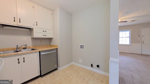 kitchen featuring light carpet, a sink, stainless steel dishwasher, a textured ceiling, and white cabinetry