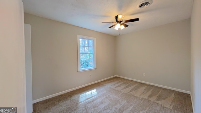 empty room featuring carpet, a ceiling fan, visible vents, and baseboards