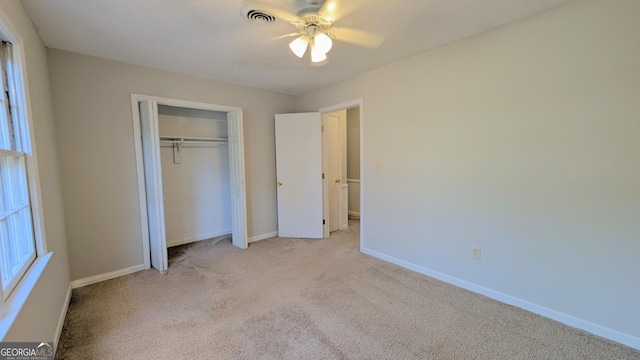 unfurnished bedroom with baseboards, visible vents, ceiling fan, a closet, and light carpet