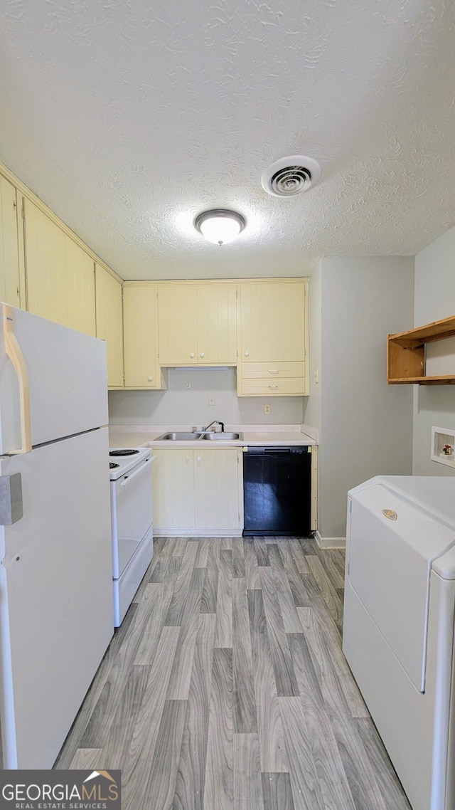 kitchen featuring visible vents, light countertops, washer / dryer, cream cabinetry, and white appliances