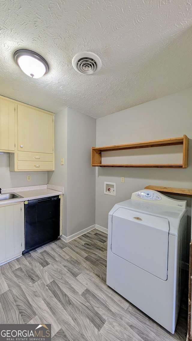 laundry area featuring visible vents, a sink, washer / clothes dryer, cabinet space, and light wood finished floors